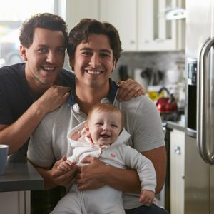 ThinkstockPhotos-524157306 Male gay couple with baby girl in kitchen looking