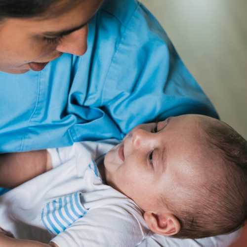 Caring nurse holds a five-month-old baby during a physiotherapy session, providing comfort and support